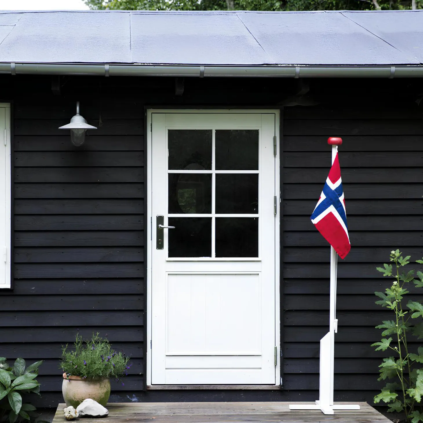 Hvitmalt flaggstang med norsk flagg, rød, hvit, blå